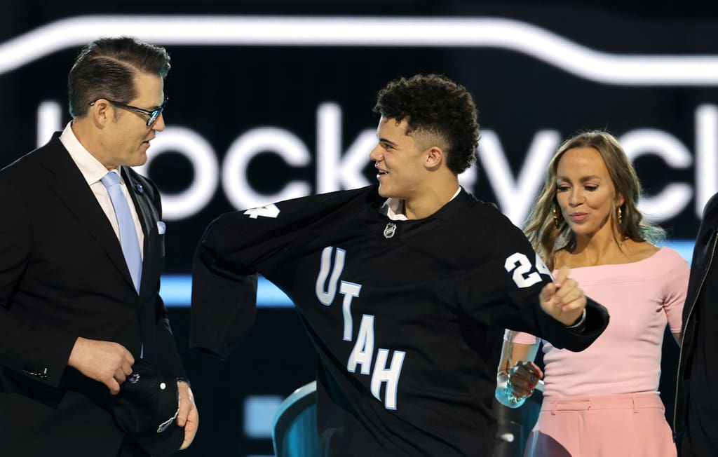 Tij Iginla, center, puts on a jersey after being selected by the Utah Hockey Club during the first round of the NHL hockey draft Friday, June 28, 2024, in Las Vegas.